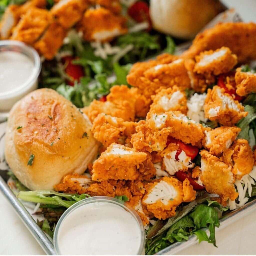 A salad with fried chicken and a side of ranch