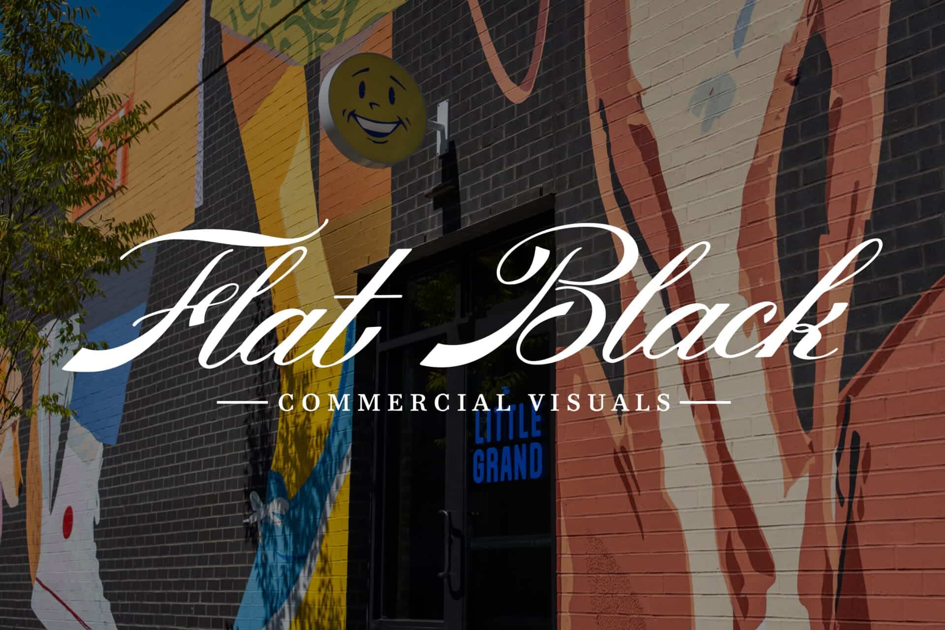 Flat Black Commercial Visuals logo over a mural at The Little Grand Market