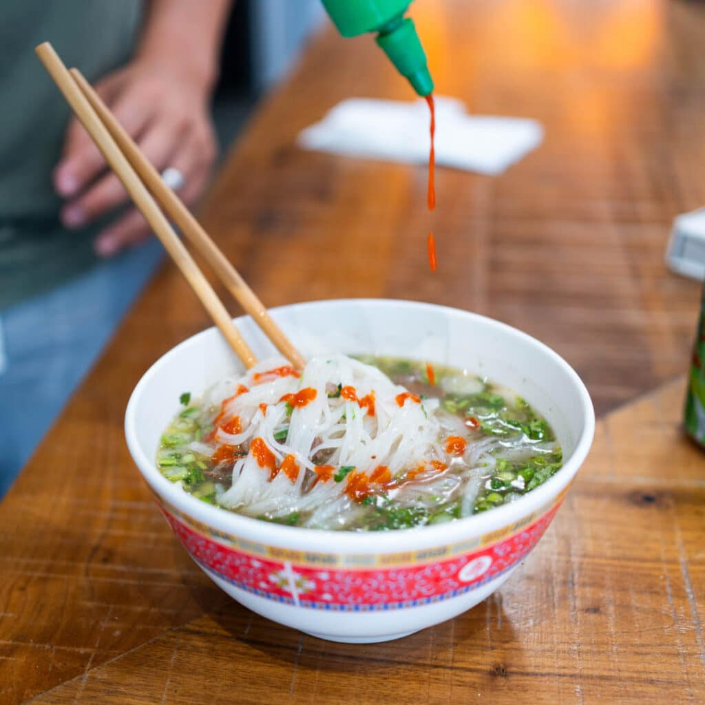 A bowl of noodles with sriracha sauce from Lan Viet