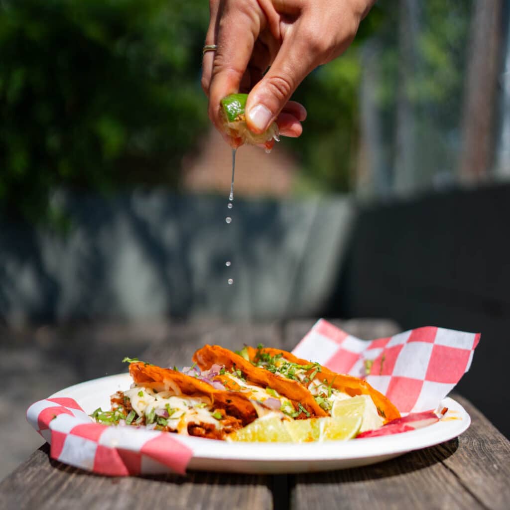 A hand squeezing a lime onto tacos from Los Agavez