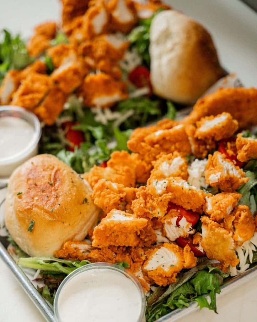 A salad with fried chicken and a side of ranch